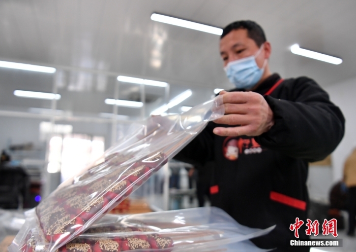1月18日，雄安新區(qū)大樹劉莊村辛愛青家中的冰糖葫蘆加工廠，工人正對(duì)冰糖葫蘆半成品進(jìn)行真空塑封。作為遠(yuǎn)近聞名的“冰糖葫蘆村”，大樹劉莊村制作冰糖葫蘆的歷史已有100多年，全村三分之二的村民都會(huì)這門手藝，吸引不少游客慕名而來(lái)。 中新社記者 韓冰 攝